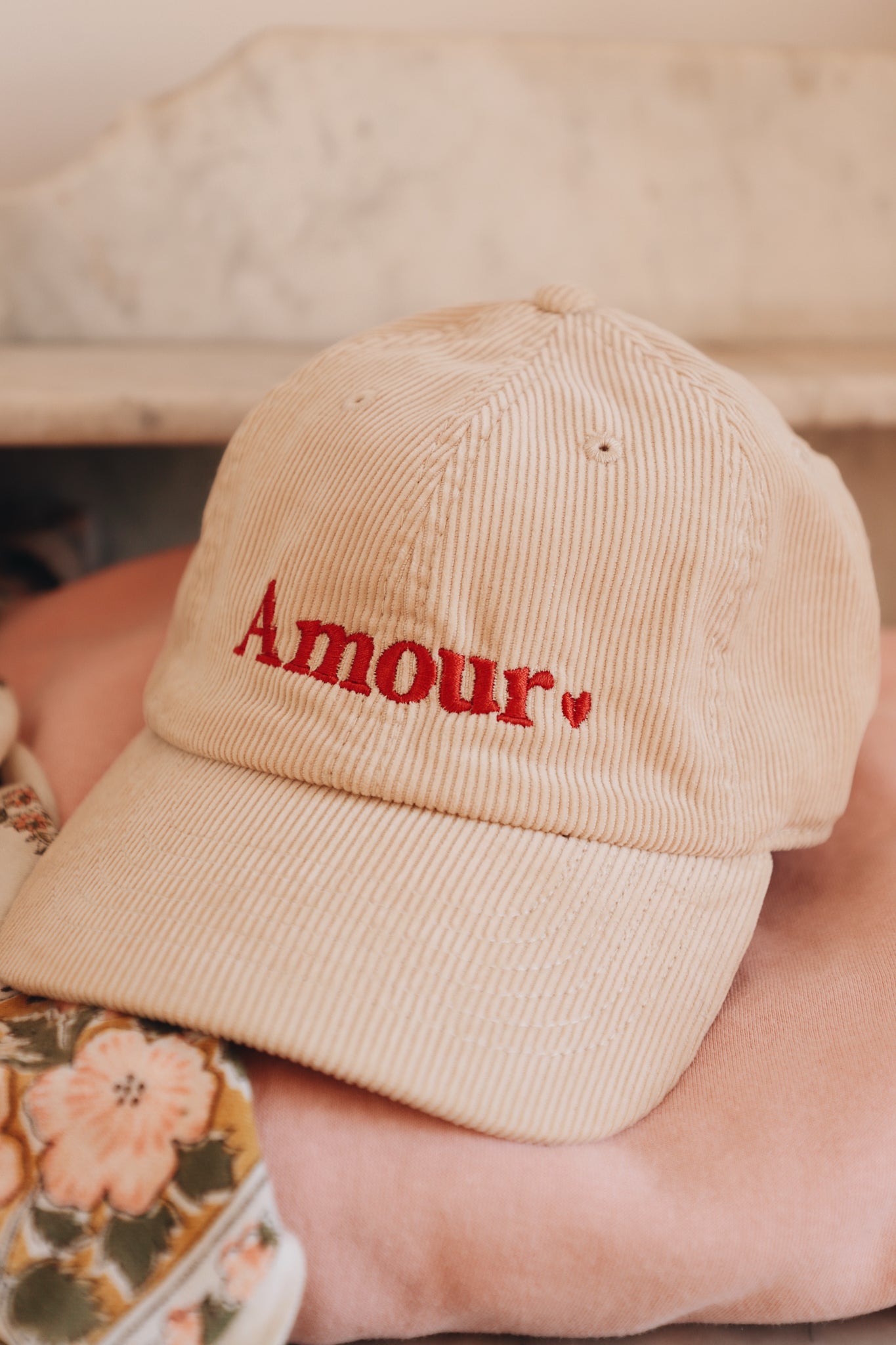 Gros plan de la broderie 'Amour' sur la casquette en velours côtelé.